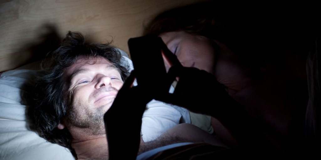 The affair. Man and woman in bed. Man is laughing at his iPhone, implying contact with another woman. His wife is asleep.